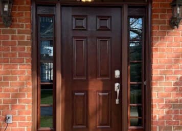 Wooden front door with glass sidelights and brick walls