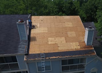 Roof replacement project with workers on stripped deck