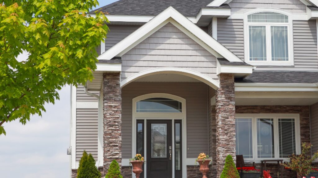 Home with grey siding, stone pillars and gabled roof