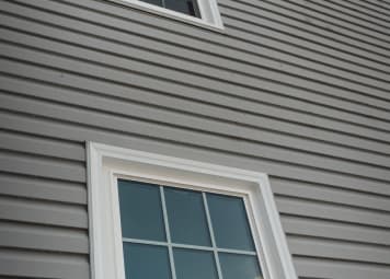Grey horizontal siding with white-trimmed window