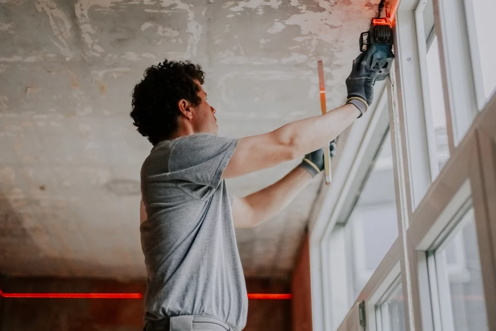 A worker on ladder installing a window.