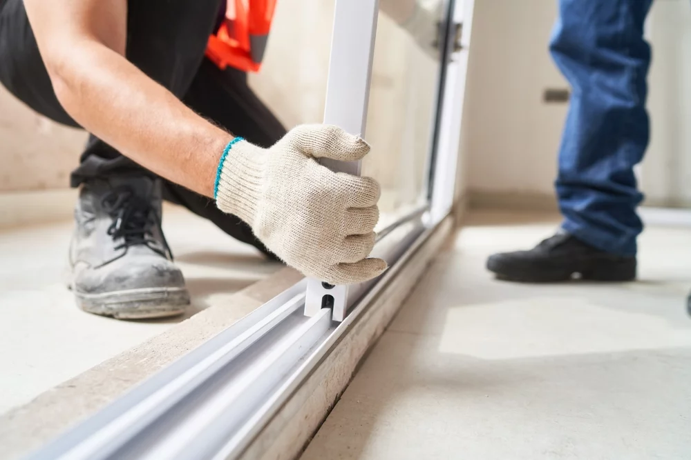 Two technicians installing a floor-length window.